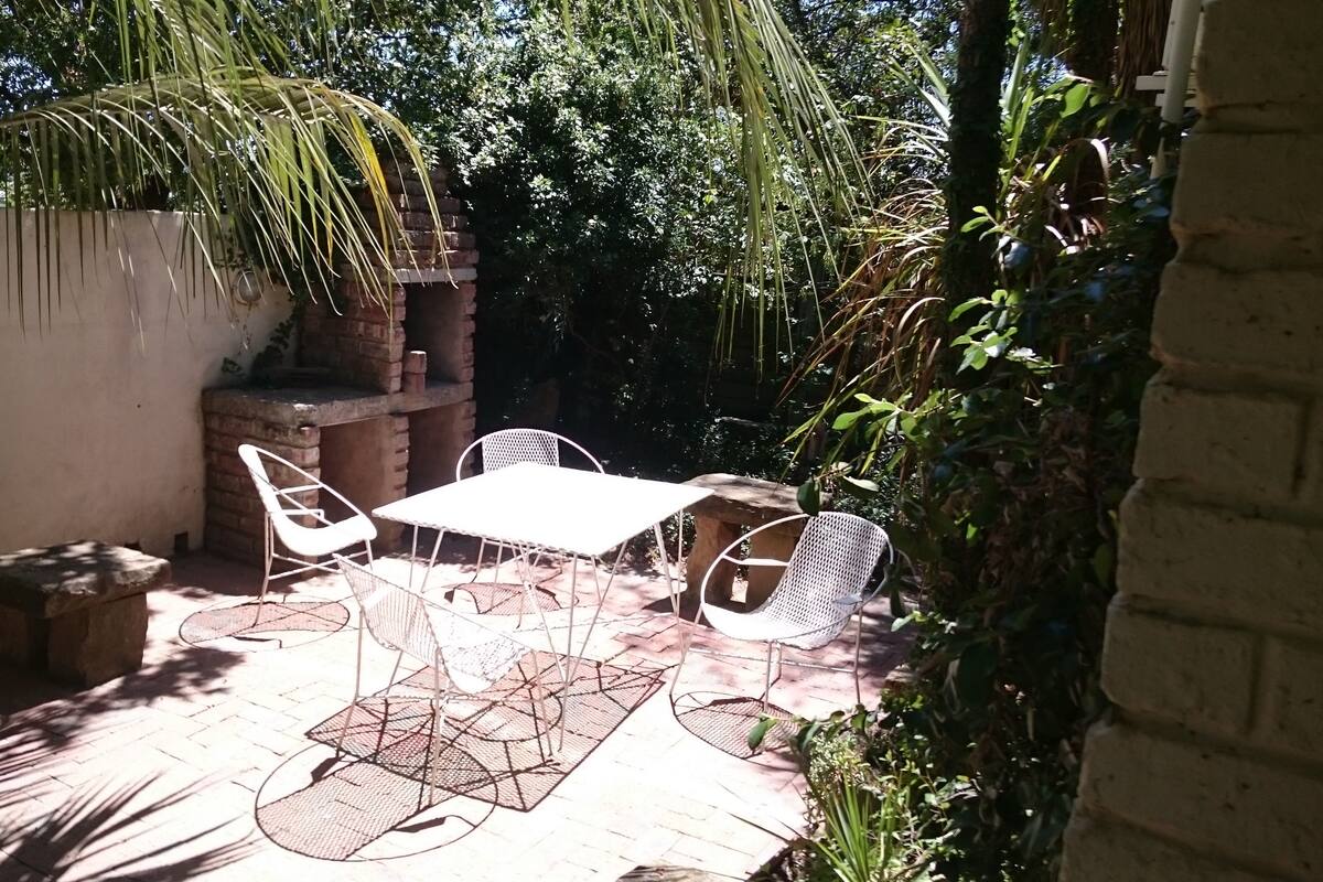 A patio with a brick wall, white metal chairs, and a table.