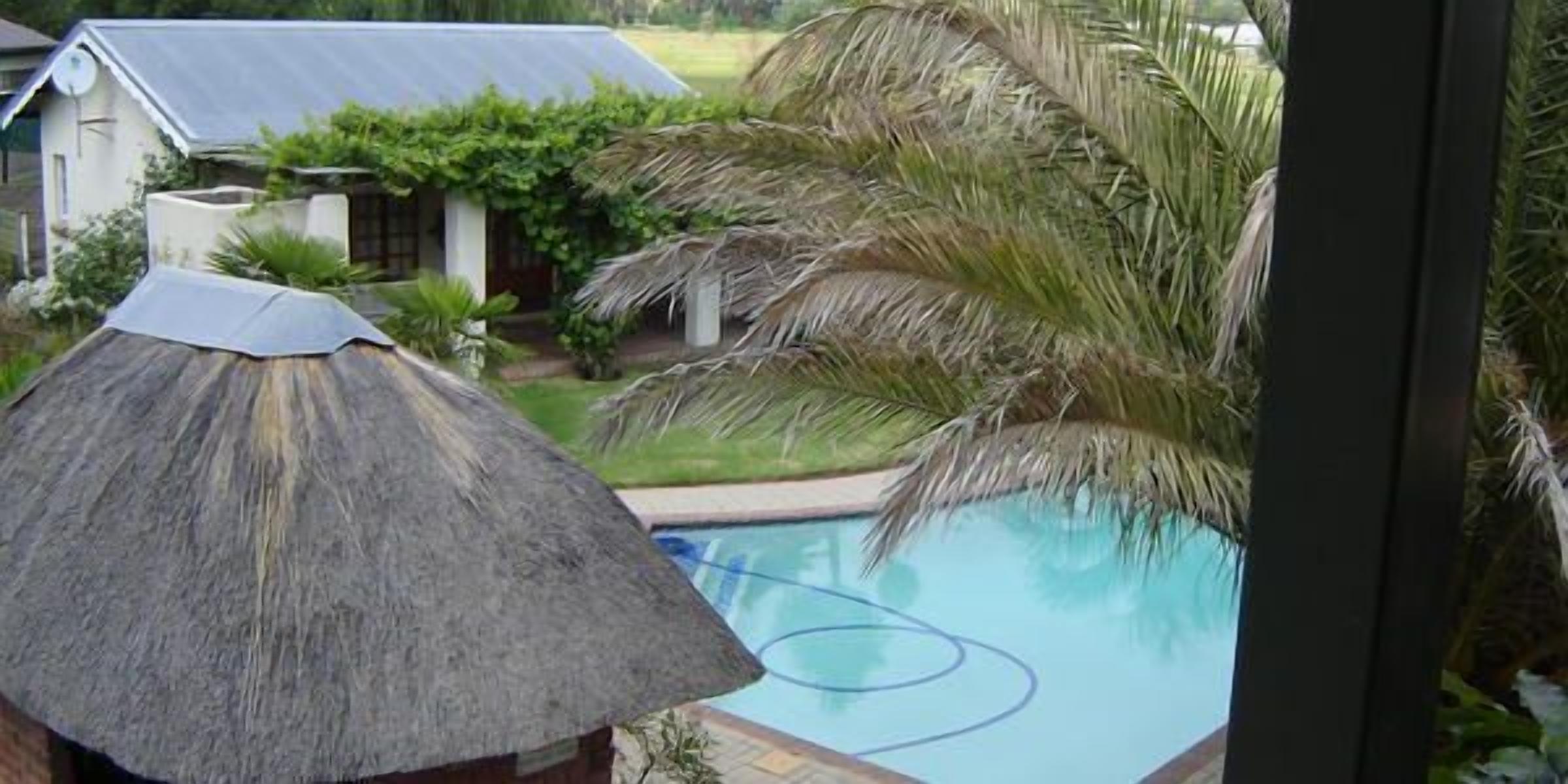 Una piscina con una estructura de techo de paja cerca.