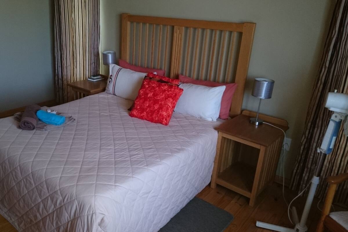 A neatly made bed with a quilted cover, a wooden headboard, and two bedside lamps.