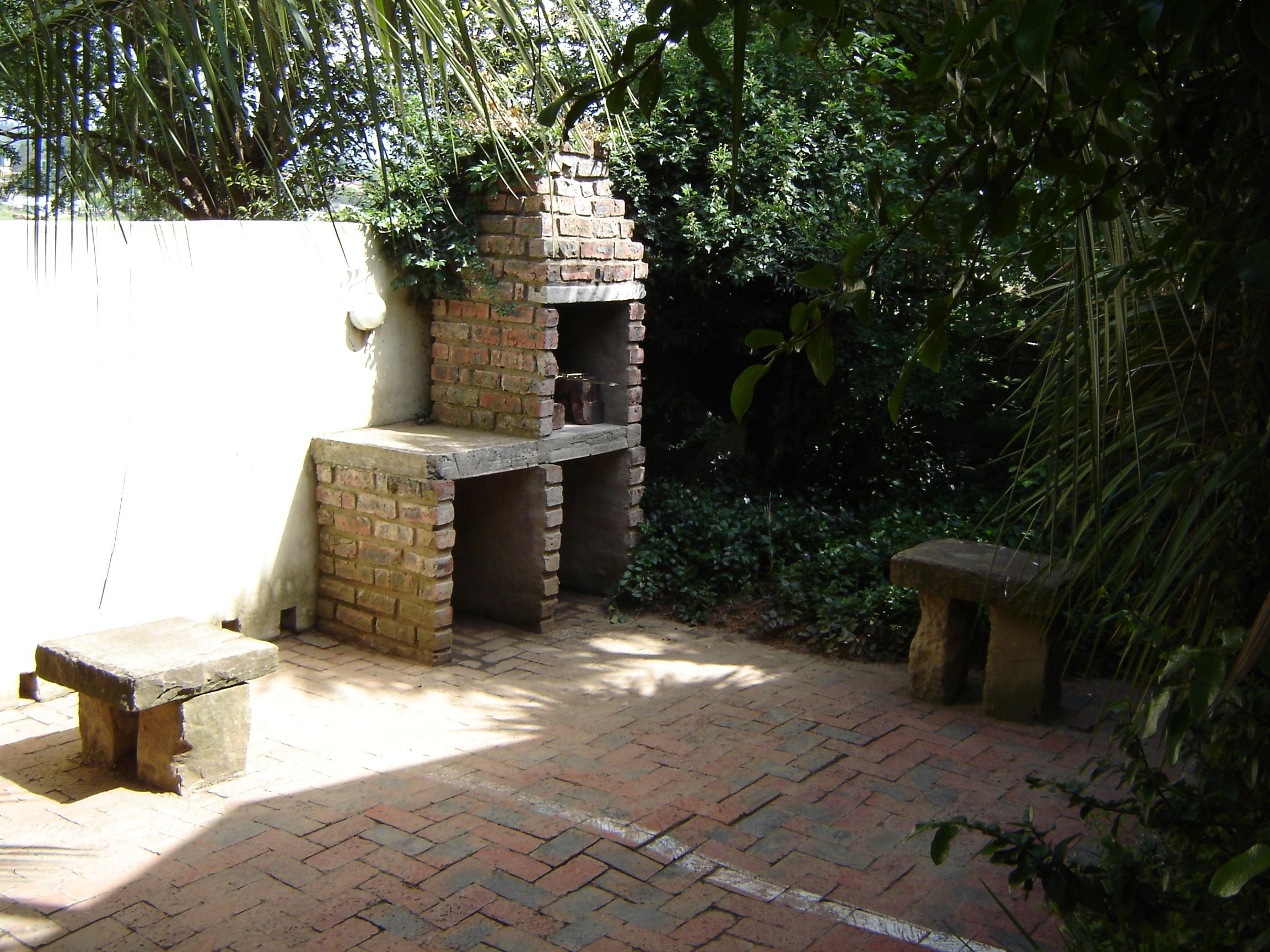 Estructura de ladrillo al aire libre con chimenea, rodeada de follaje.