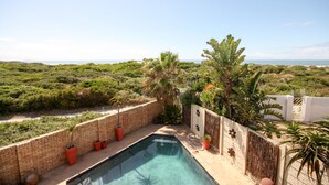 A rooftop pool with a view of a coastal landscape, surrounded by greenery and a brick wall. - House Haven Guesthouse (Gqeberha (Port Elizabeth))