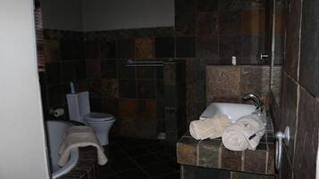 Casa de banho com sanita, lavatório e zona de duche.