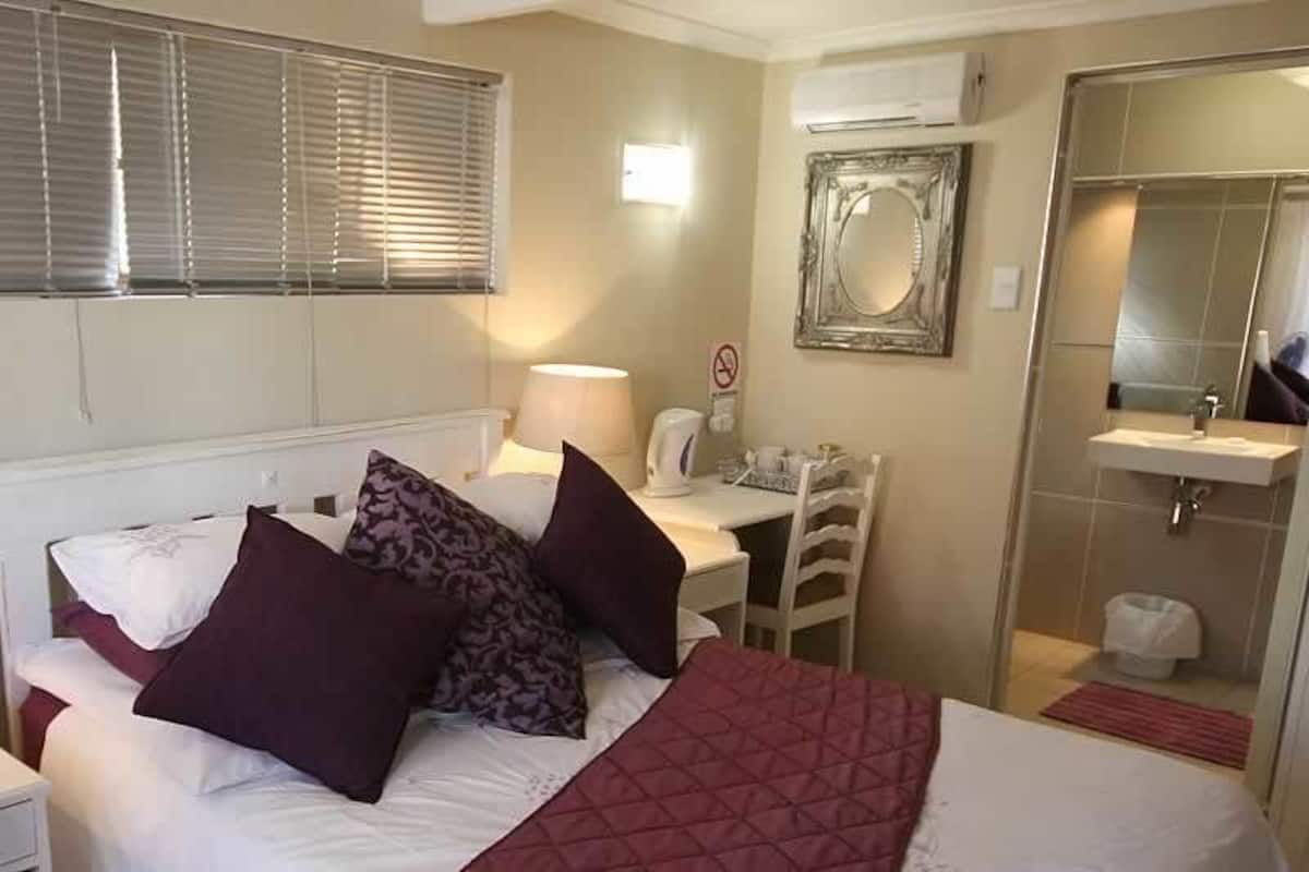 Una camera d'albergo con un letto, comodini, una scrivania, uno specchio e un televisore.