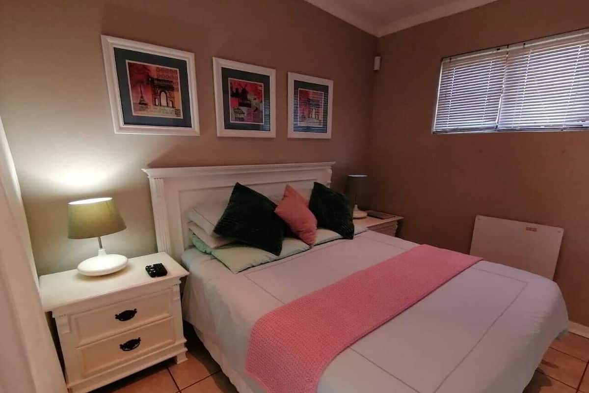 Una camera da letto con un letto, un comodino, una lampada e tre quadri appesi al muro.