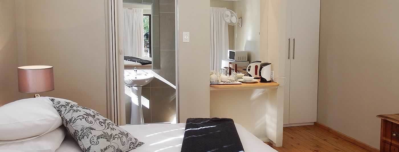 Una camera da letto con un letto, una lampada da comodino e vista sul bagno.