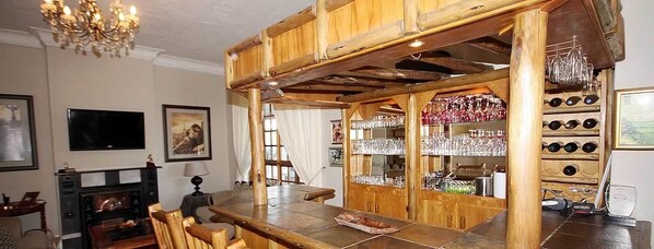 Un coin bar rustique en bois, avec une cheminée, un téléviseur et des tableaux encadrés accrochés au mur.