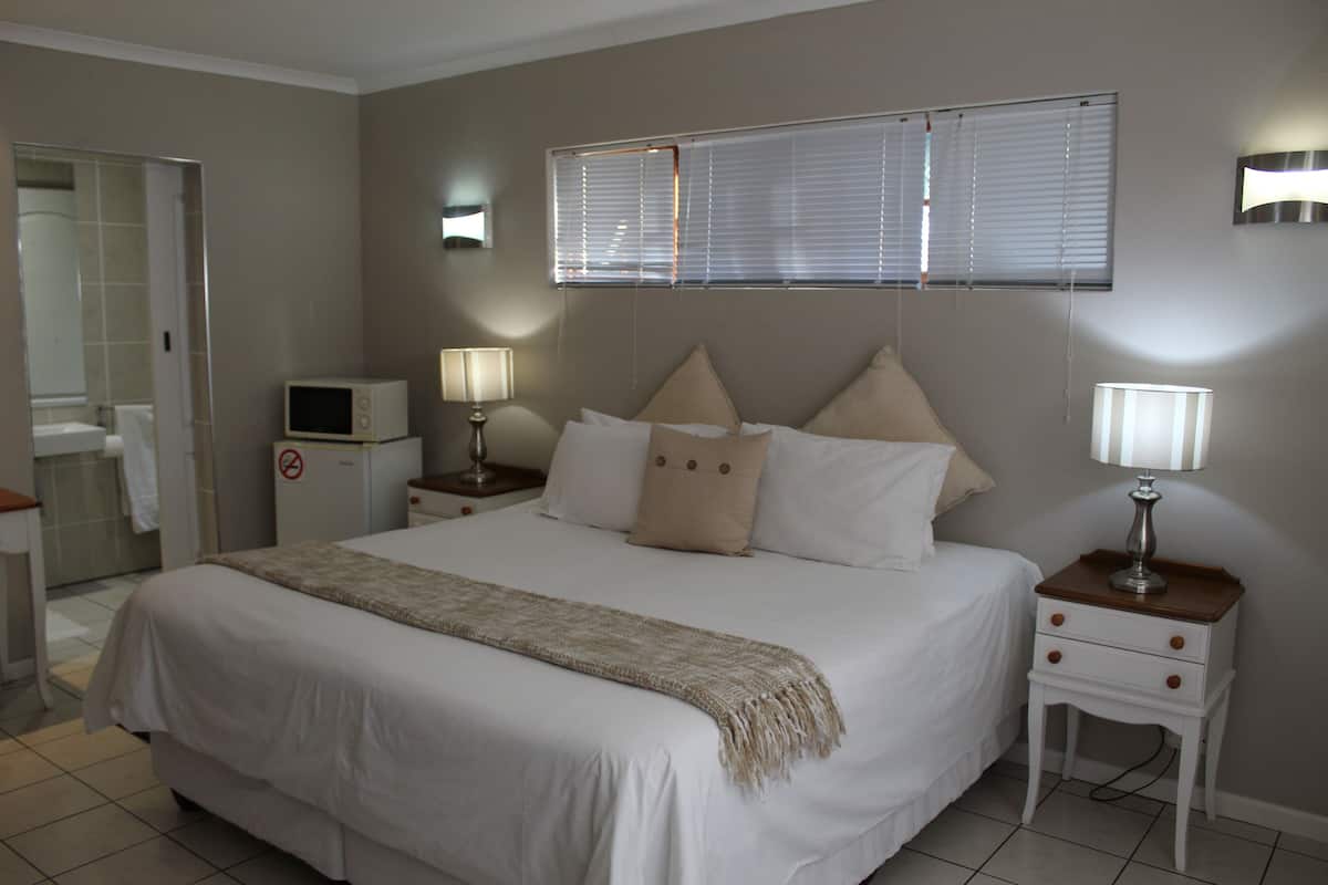 Una camera da letto ordinata con un letto, comodini, una TV e un bagno visibile sullo sfondo.
