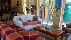 Una sala de estar acogedora con un sofá blanco, una mesa de centro de madera y un sofá estampado en rojo y naranja.