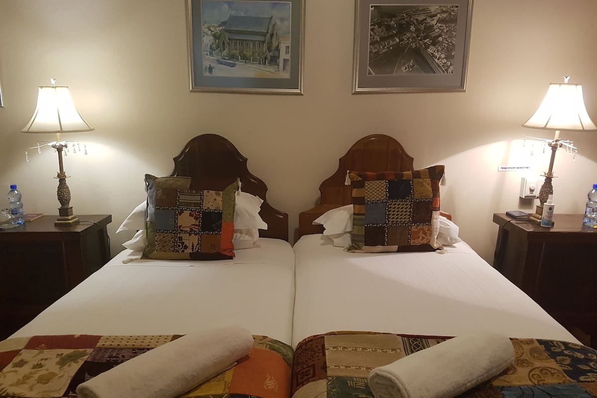 A double bed with a quilt, two nightstands with lamps, and two framed pictures on the wall.