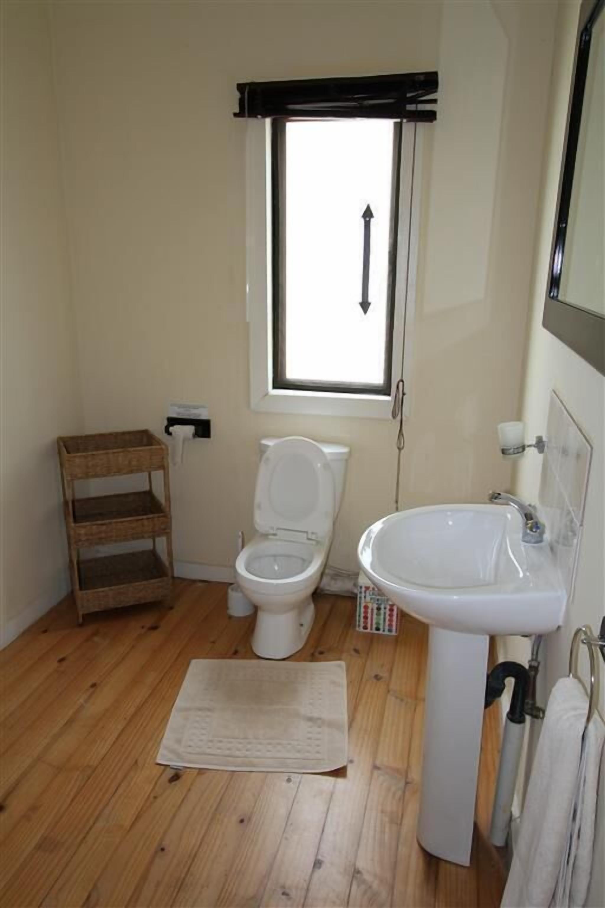 A small bathroom with a toilet, sink, and window.