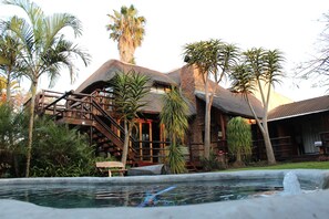 A resort with a pool, wooden deck, and palm trees.