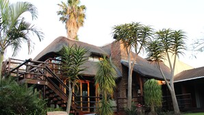 A resort with a thatched-roof building, wooden staircase, and a pool area. - Tidewaters Accommodation (East London)