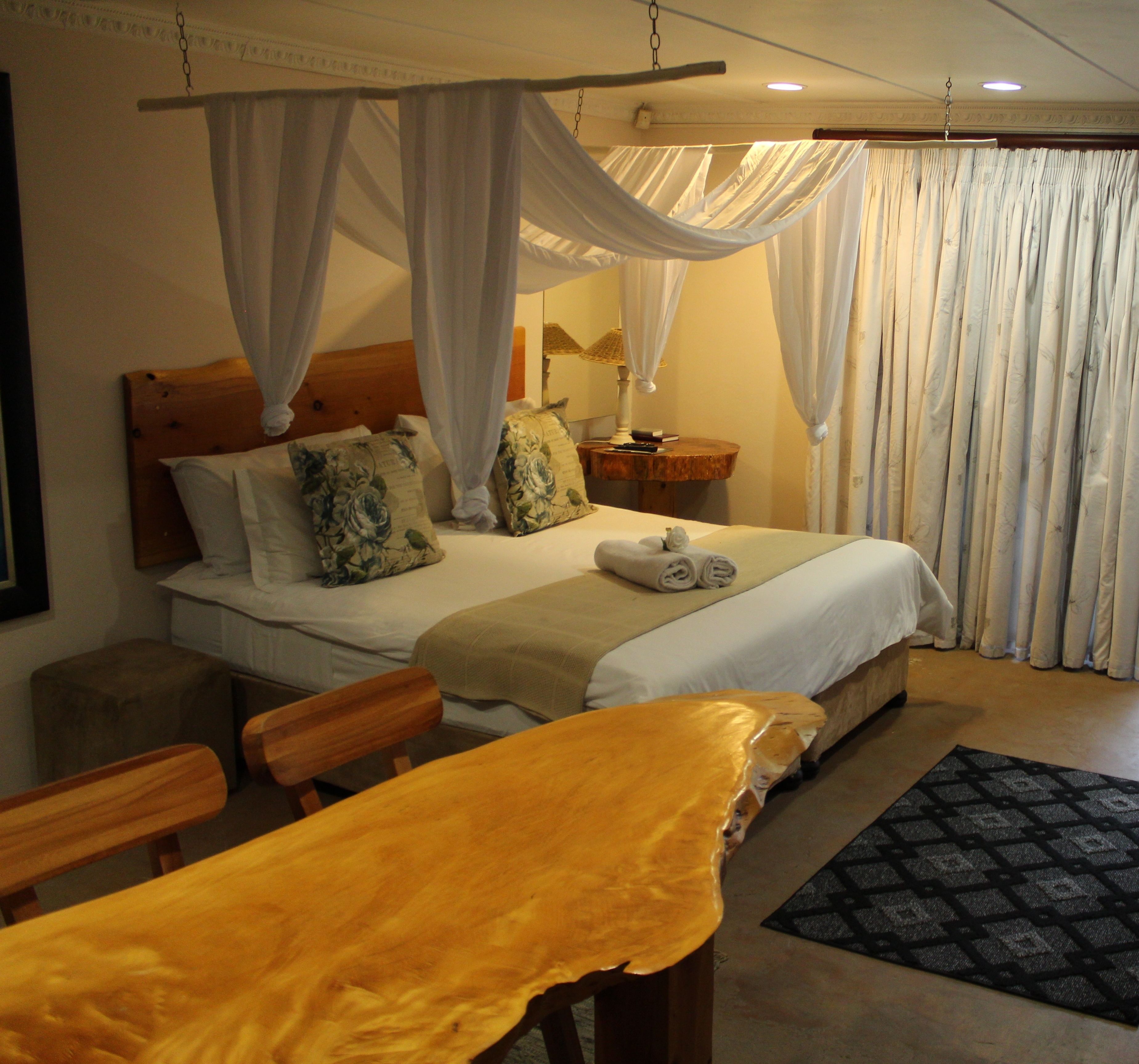 A bedroom with a bed, a bedside table, a lamp, a chair, and a bench.