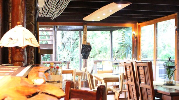 A restaurant interior with wooden furniture, large windows, and a ceiling with exposed beams. - Tidewaters Accommodation (East London)