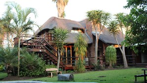 A house with a thatched roof, wooden staircase, and a swimming pool. - Tidewaters Accommodation (East London)