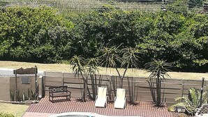 Um quintal com piscina, deck de madeira e cadeiras de descanso.