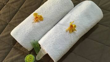 Two white towels with yellow flowers on a brown quilted bedspread.