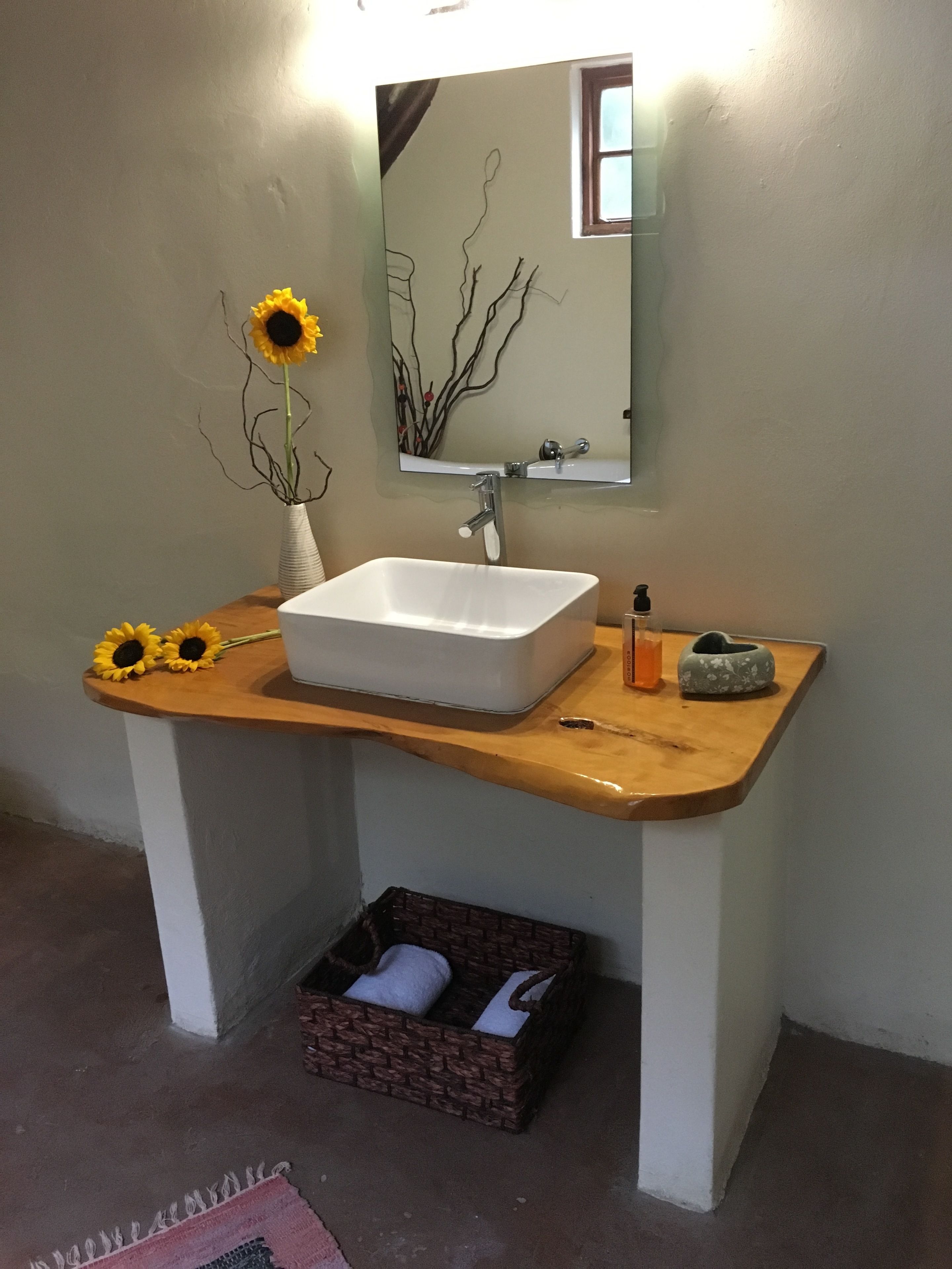 A bathroom with a white sink, a mirror, and a vase with sunflowers.