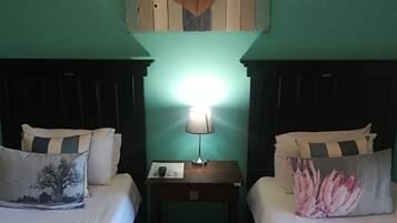 Una habitación con dos camas, una mesita de noche con una lámpara y un adorno de corazón en la pared.