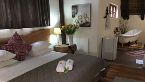 Uma cama bem arrumada com colcha acolchoada, duas toalhas enroladas com flores e um vaso com flores amarelas em uma mesa de cabeceira.