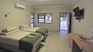 Habitación de hotel con dos camas, televisor y escritorio con cafetera.