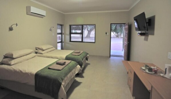 A hotel room with two beds, a TV, and a desk with a coffee maker.