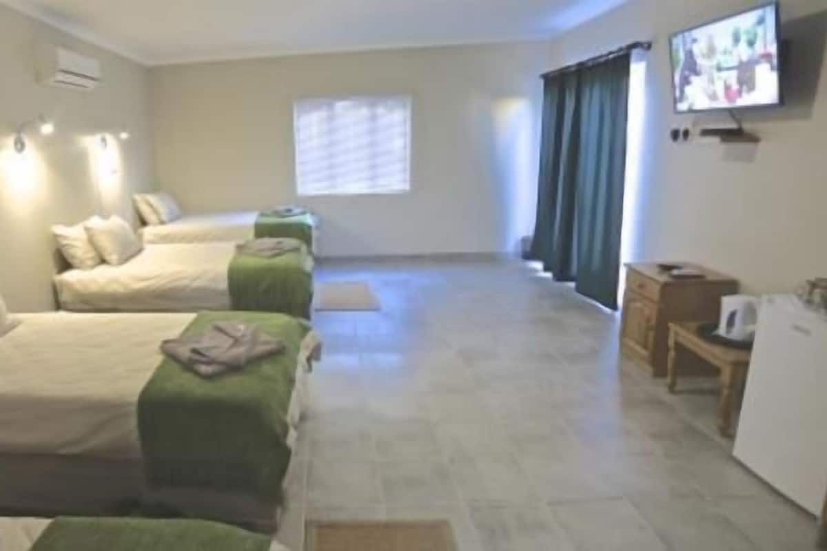A hotel room with two beds, a television, and a kitchenette.