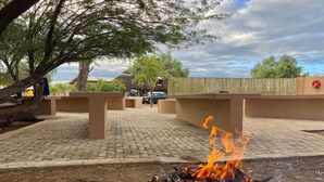 Una parrilla con llamas, un área pavimentada y una cerca.