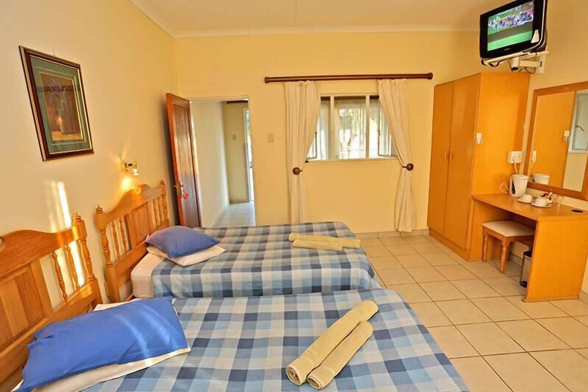 A hotel room with two beds, a desk, a television, and a mirror.