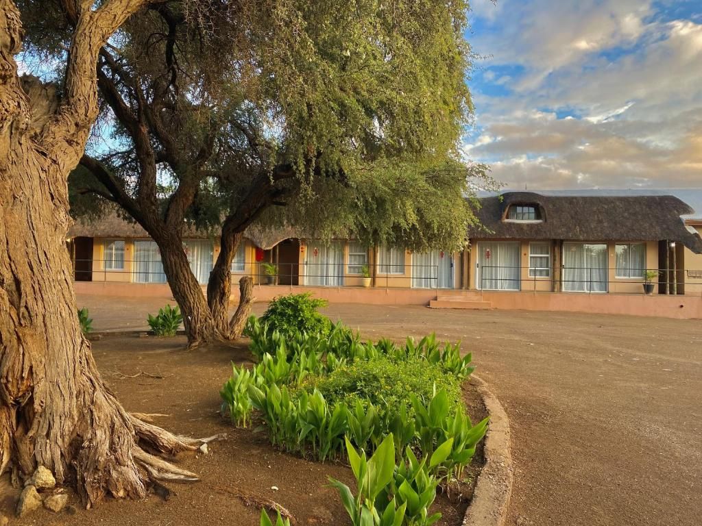 Un edificio con varias habitaciones, un árbol grande y un jardín.