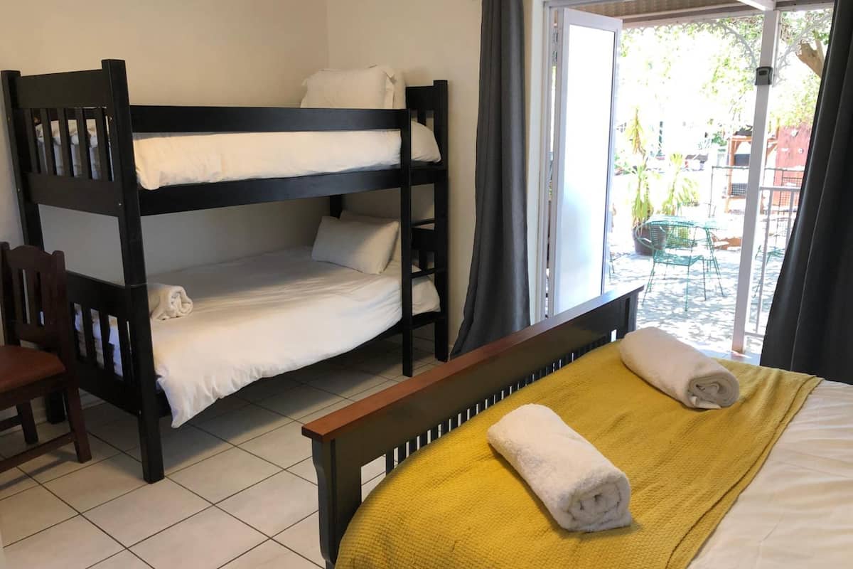Dormitorio con literas, una colcha amarilla y una toalla enrollada.