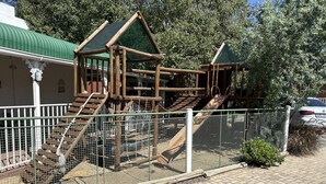 A playground with wooden structures and a fenced area.