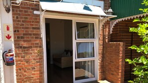 A residential entrance with a brick exterior, a white awning, and a fire extinguisher mounted on the wall.
