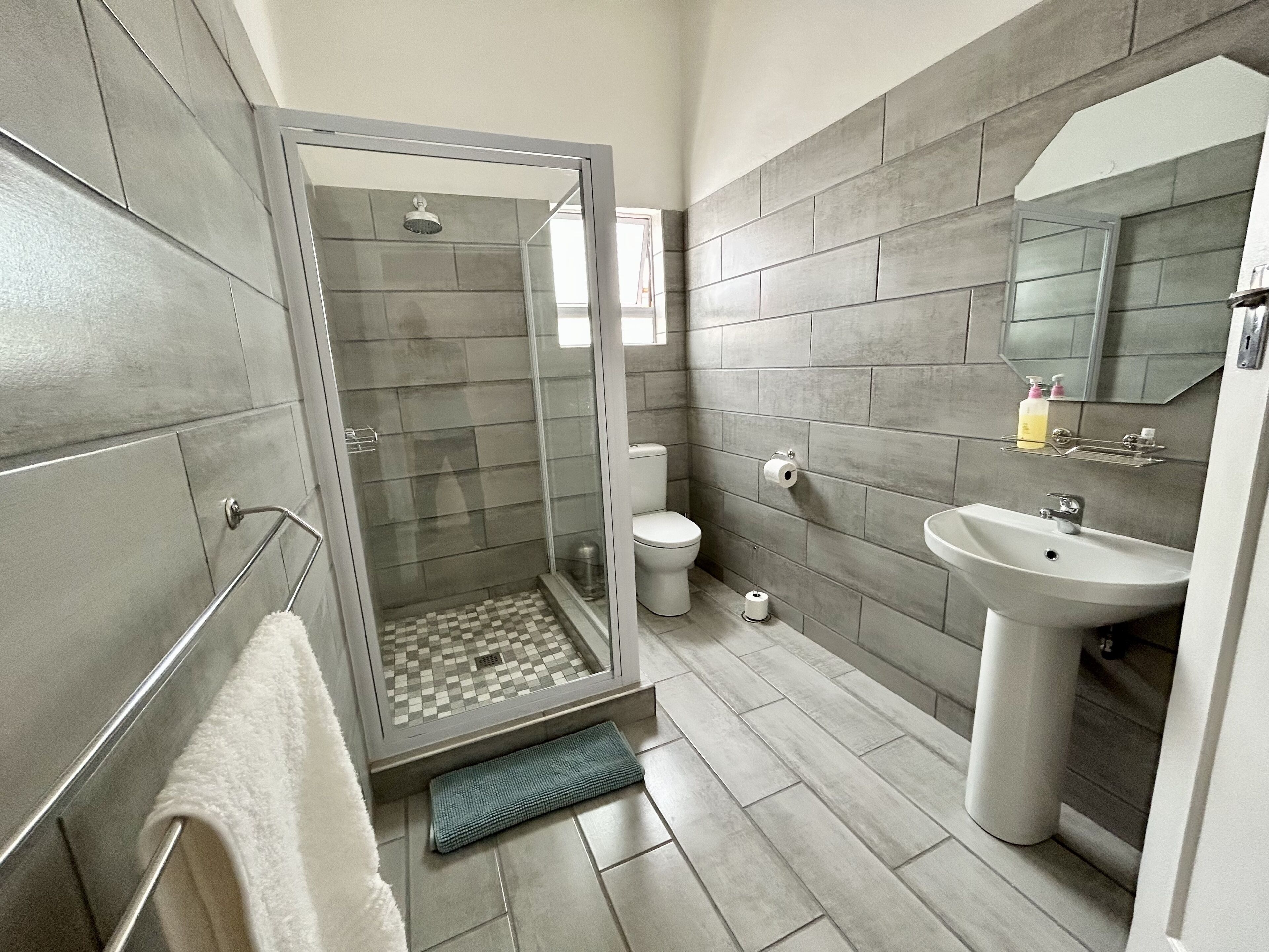 A modern bathroom with a shower, toilet, and sink.