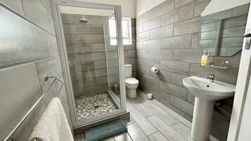 A modern bathroom with a shower, toilet, and sink.