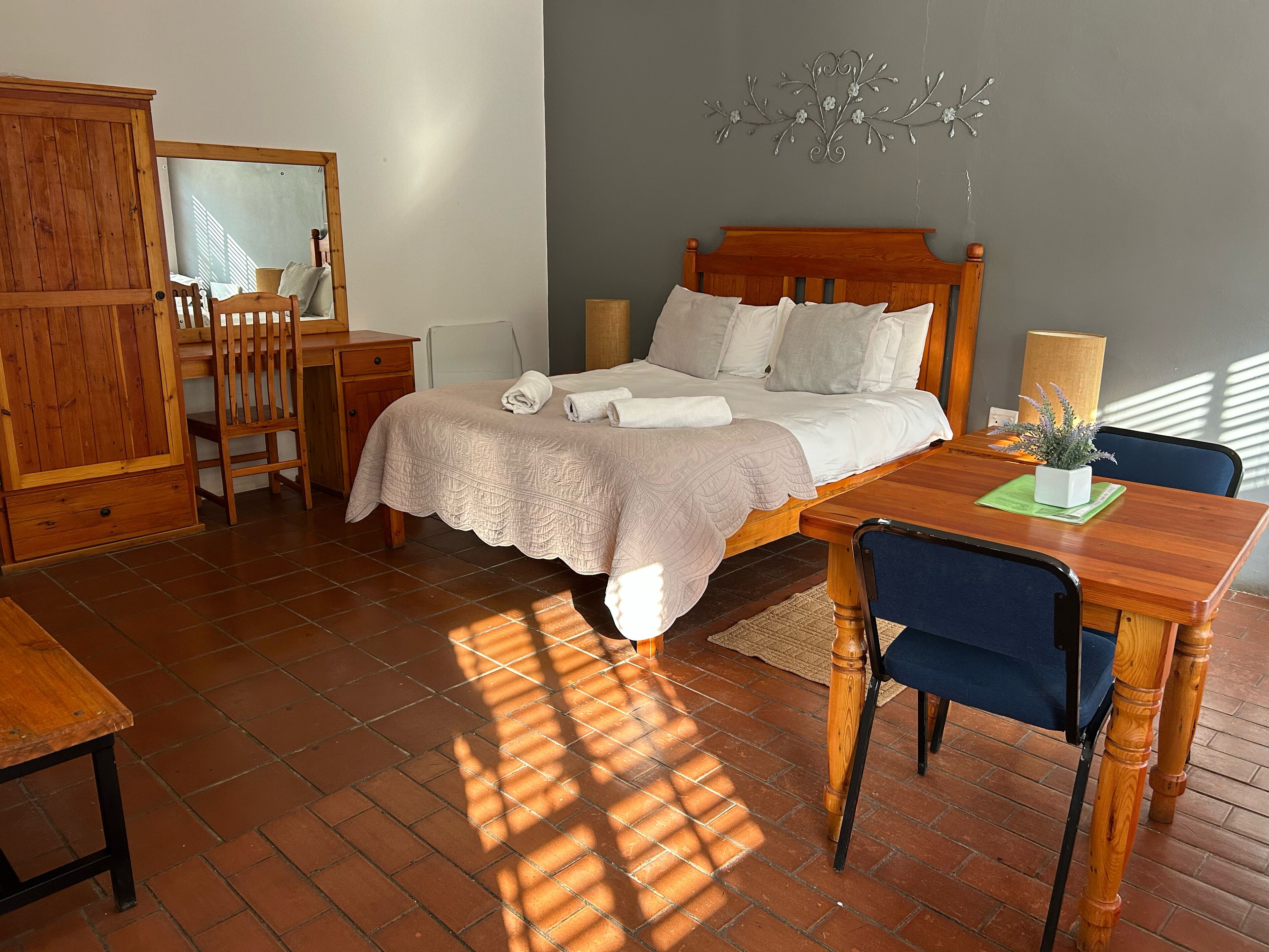 Un dormitorio con una cama de madera, un escritorio, una silla, un armario y un espejo.
