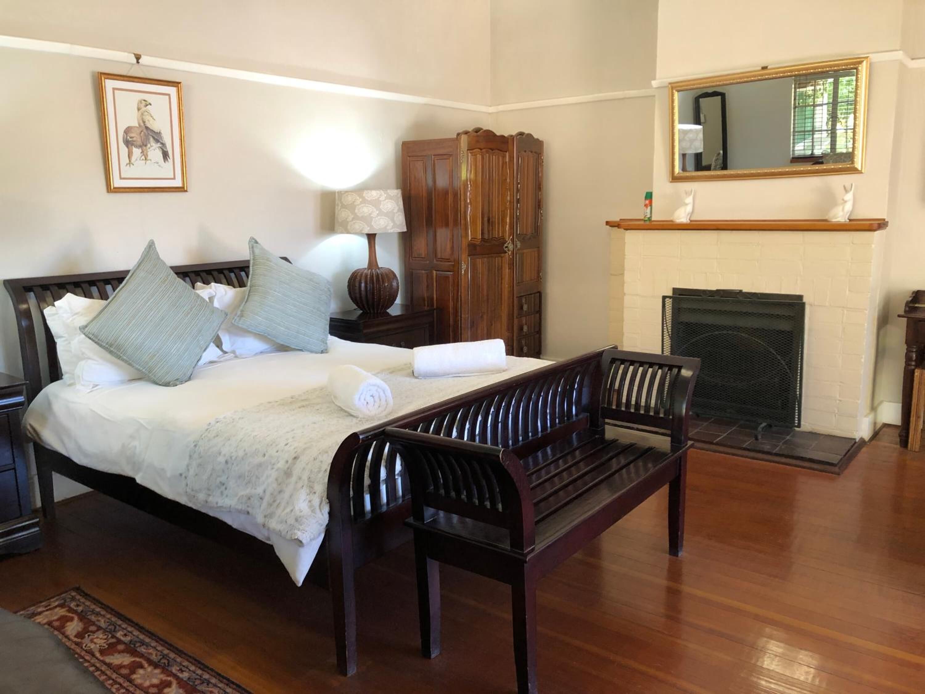 Une chambre à coucher avec un lit, des meubles en bois, une cheminée et un miroir.