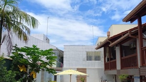 Zona residencial con piscina, rodeada de exuberante vegetación y un cielo azul despejado.