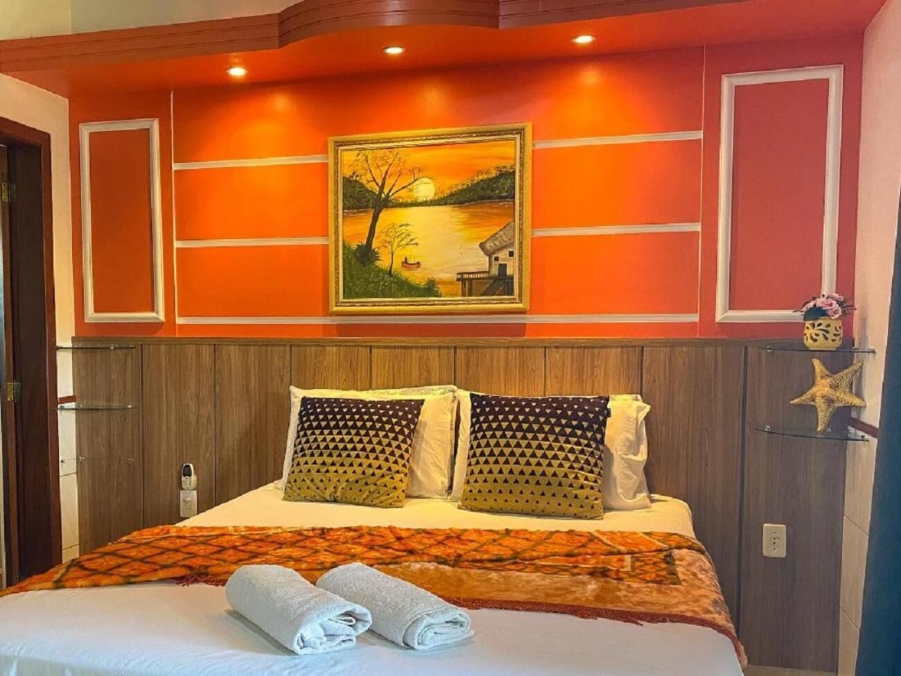Quarto de hotel com cama, um quadro na parede e decoração de estrela-do-mar.