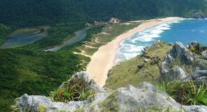 A coastal landscape with a sandy beach, a river, and dense greenery. - Pousada Arquipelago (Florianópolis)