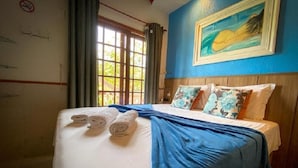Habitación de hotel con cama, toallas, un cuadro y una ventana con cortinas.