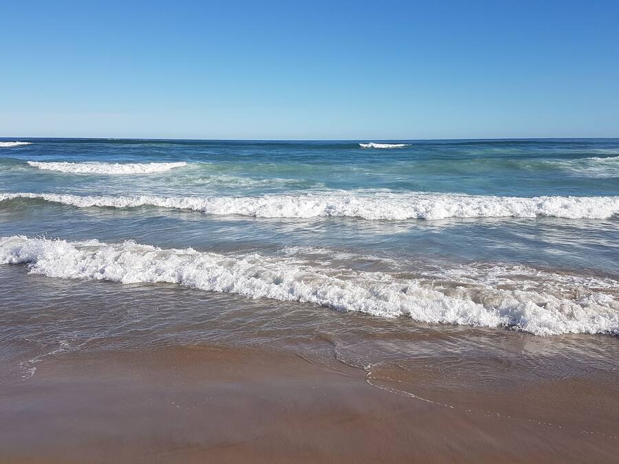 Na praia, areia branca, guarda-sóis, toalhas de praia
