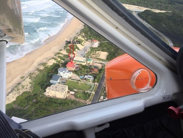 Une vue aérienne d’une zone côtière avec une plage, des bâtiments et une route.
