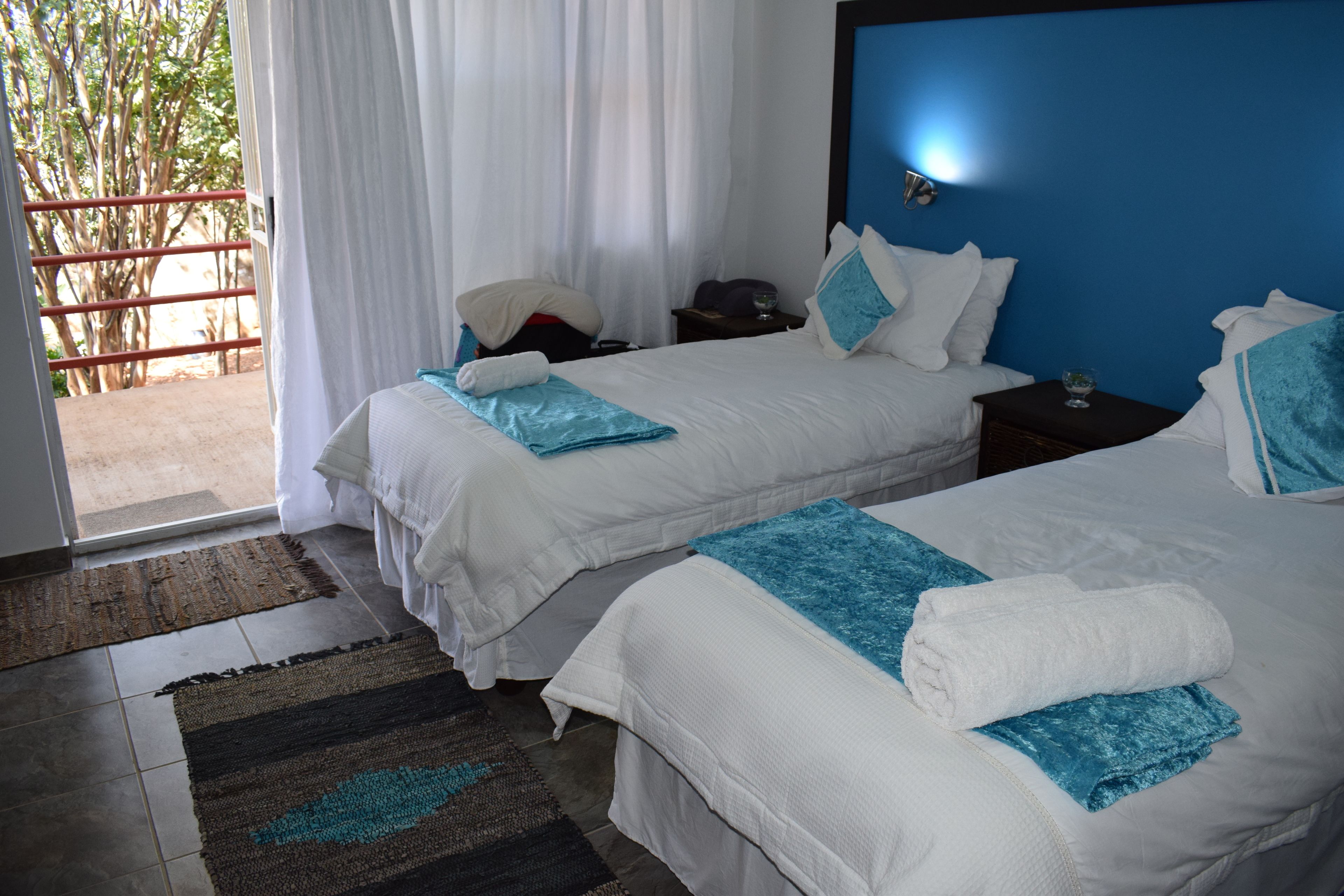 A hotel room with two beds, a nightstand, and a view of an outdoor area.