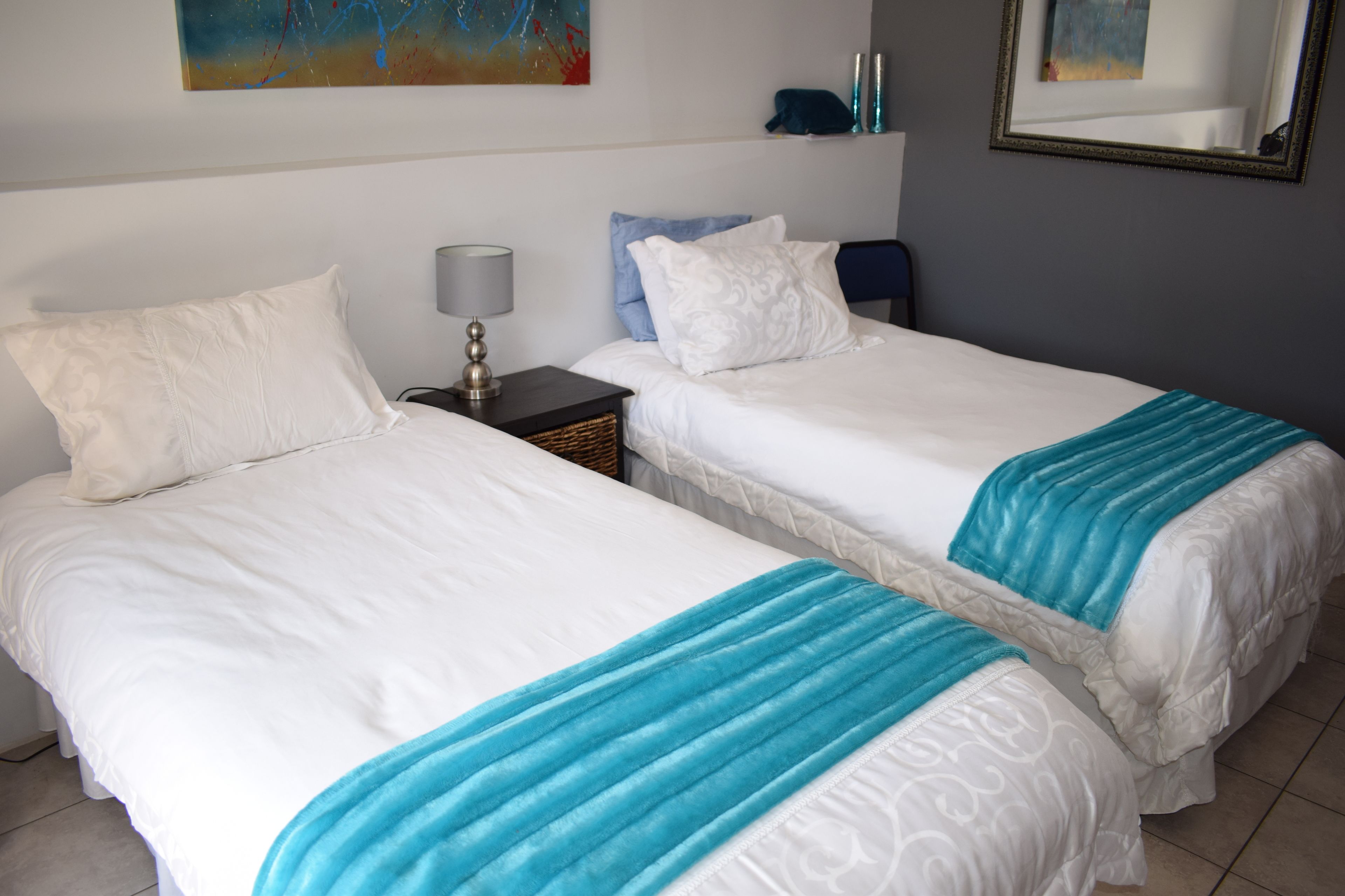 Une chambre d’hôtel avec deux lits, chacun agrémenté de draps blancs et d’un élément décoratif bleu.