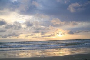 Une plage avec des vagues et un ciel nuageux.