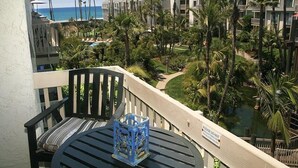 Ein Balkon mit Blick auf ein Resort, darunter ein Pool und Palmen.