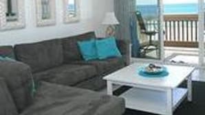 Une pièce avec un canapé, une table basse et une vue sur l’océan.