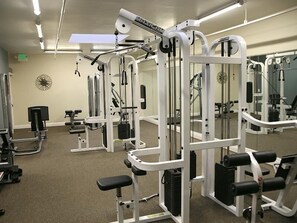 A gym with various exercise machines, including a squat rack and a bench press. - Seascape Stay (Oceanside)