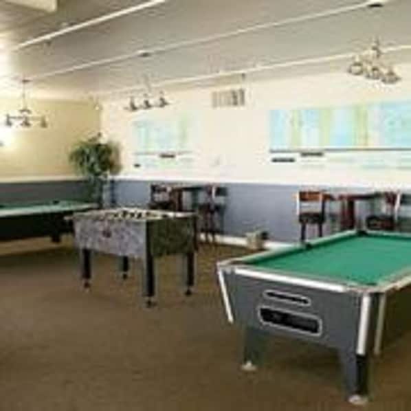 A billiards room with multiple pool tables, a green carpet, and a white ceiling.